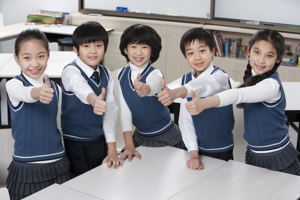 Chinese students giving thumbs up in the classroom